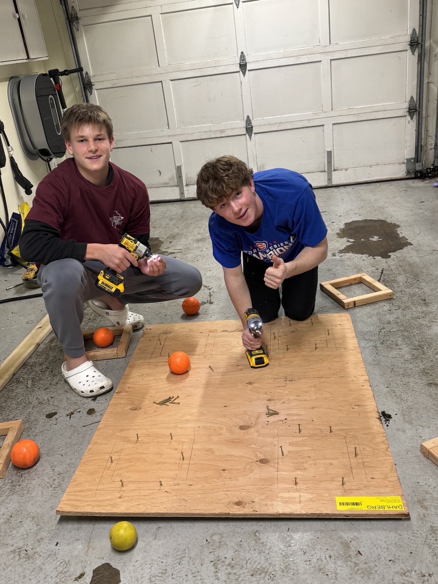 Two Destination Imagination teammates building with plywood and drills
